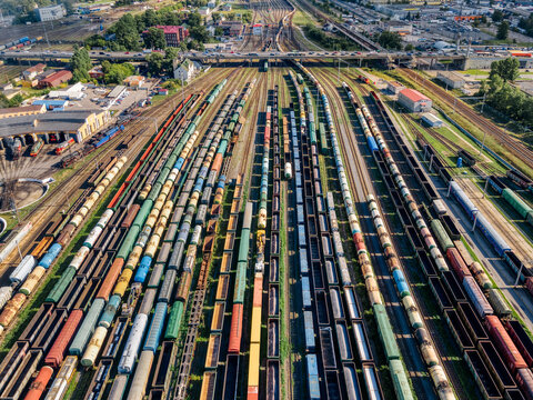 Aerial photo of lots of various wagons: tanks, platforms, dump trucks, dumpcars stay on railways at terminal. Cargo transportation of various goods by rail. Import and export logistics.