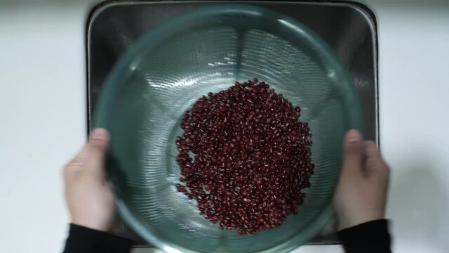 top down view of red beans being cleaned at kitchen sink