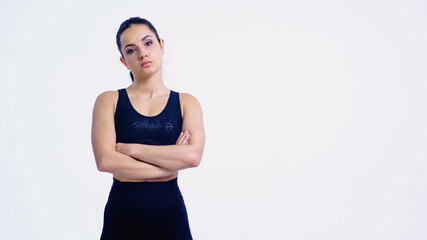 displeased and athletic woman standing with crossed arms isolated on white