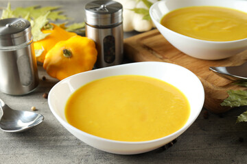 Concept of tasty food with pumpkin soup on gray textured table
