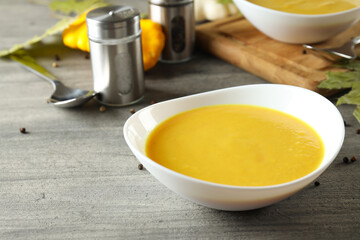 Concept of tasty food with pumpkin soup on gray textured table
