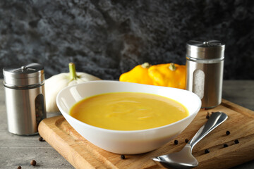 Concept of tasty food with pumpkin soup on gray textured table