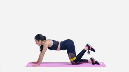 side view of brunette young sportswoman working out with elastics on pink fitness mat on white