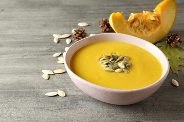 Concept of tasty food with pumpkin soup on gray textured table