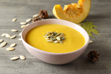 Concept of tasty food with pumpkin soup on gray textured table