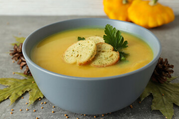 Concept of tasty food with pumpkin soup on gray textured table
