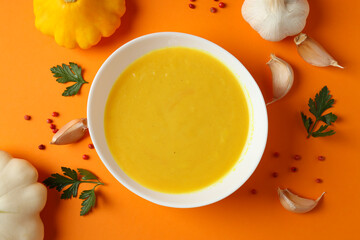Concept of tasty food with pumpkin soup on orange background