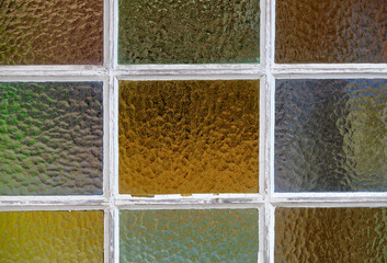 Close-up of a beautiful multicolored old muntin window with white frame. Seen in Germany in July.
