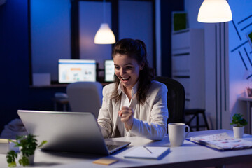 Business woman looking at professional laptop working at marketing graphs project late at night. Workaholic manager planning financial strategy using technology network wireless at company office