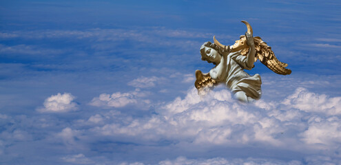 An angel in the blue sky holds the moon in his hands. Fragment of an ancient statue.
