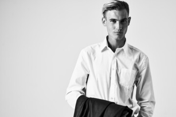 man in white shirt with jacket in hands cropped view light background