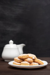 Appetizing shortcakes on teapot and jug background. Homemade shortbread cookies. Baking for tea. Vertical frame