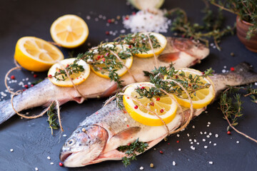 Raw fish on a dark background. The fish is cooked with lemon and thyme, spices. Dinner with stuffed fish. Fresh catch. Seafood Food Styling