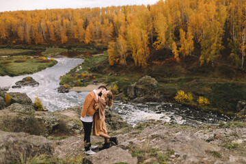 A happy couple in love in casual clothes travel together, hike and have fun in the autumn forest, enjoy nature on a weekend in fall. A man and a woman on a romantic date countryside