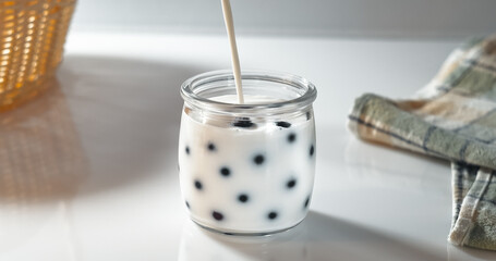 Milk is poured into a jar with fresh berries. Preparation of natural homemade yogurt in the morning for breakfast