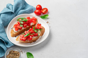 Two fried toast with tomatoes, cream cheese, herbs and butter on a gray background.