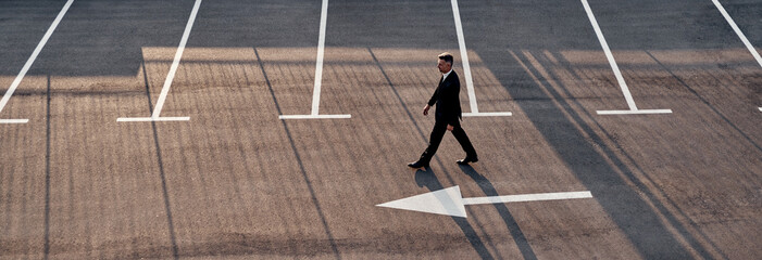 Top view of man in formalwear moving forward with arrow sign on the road