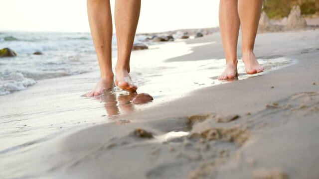 Young couple walking barefoot along the seashore