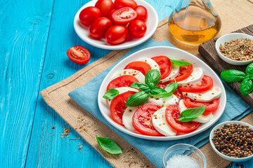 Caprese salad with tomatoes and mozzarella cheese on a blue background.