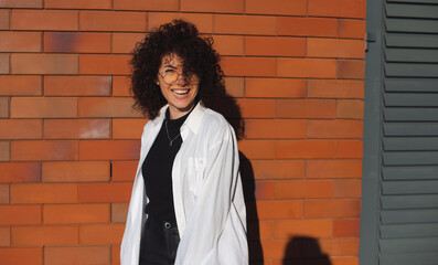 Curly black hair woman posing on a brick wall. Beautiful female person. Style and fashion concept