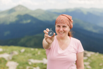 Happy Woman holding a compass in hand on nature background, ready to travel, keep calm. Tourism, traveling, hiking and healthy lifestyle concept. Focus on hand