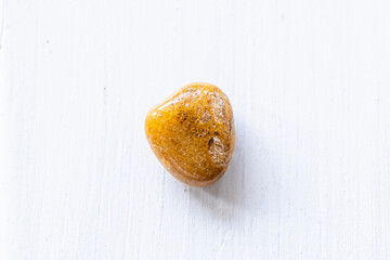 Pierre roulée polie jaspe jaune sur un fond blanc - Minéral naturel	