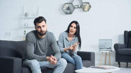displeased woman quarreling with distracted man in living room