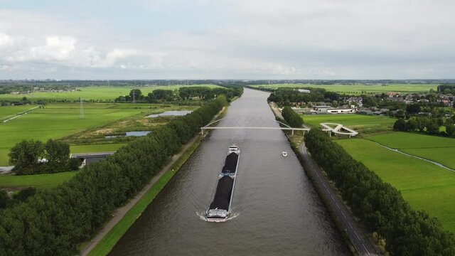 Pedestrian and cyclist bridge over the Amsterdams Rijn Canal,  waterway in Nigtevecht The Netherlands. Liniebrug. Big ship.
