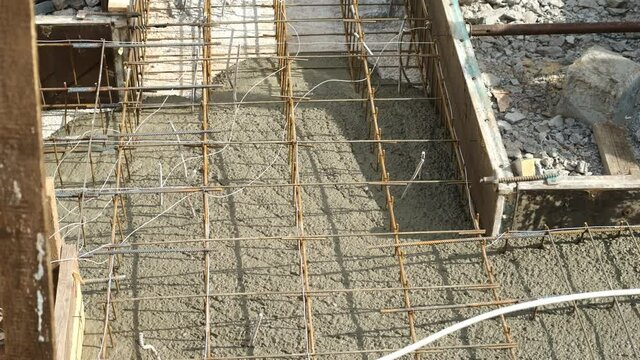 Floor of building under construction starting with concrete slab pouring. Rusty metal wiring is laid on the ground of house under construction. Preparation for making foundation of a building.