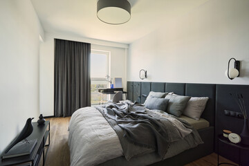 Stylish composition of small modern bedroom interior. Bed, creative lamp and elegant personal accessories. Walls with black panels. Panoramic windows. Minimalistic masculine concept. Template...