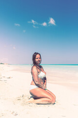 Fototapeta na wymiar Portrait of a tanned girl sitting on the beach in a swimsu