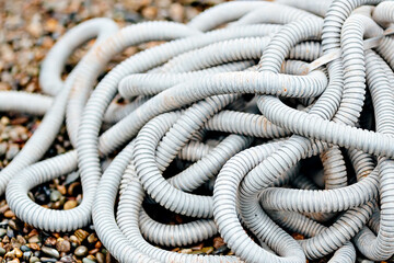 Plastic corrugated hose for insulation of wires lies on the crushed stone. Background