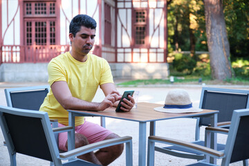 Tourist using the smartphone sitting on a bar summer terrace.
