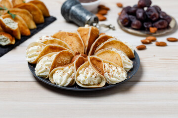 Qatayef With Almond Cream On Black Plate Isolated On White Wooden Background. Ramadan Food Concept.