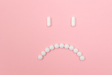 Pharma Harm. Sad Smiley Face Made from White Pills, Lying on Pink Backgrond. Global Pharmaceutical Industry and Medicinal Products