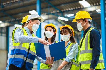 The factory employee consists of engineers, foreman, technicians, and related department staff. Wear a mask, hard hat, and vest. meeting before starting work inside the warehouse. Teamwork concept.