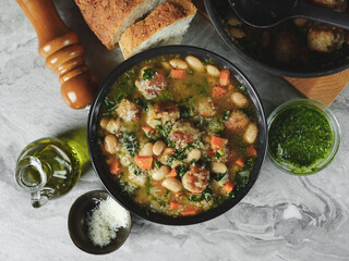 Top view soup cooking with meatballs cutlets and vegetables in big pot on home kitchen background. Copy space, closeup. Homemade food recipe concept.
