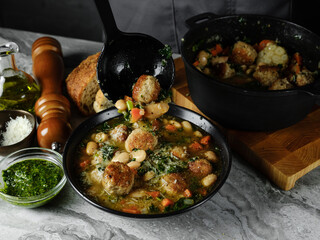 Homemade soup cooking with meatballs cutlets and vegetables in big pot on home kitchen background. Copy space, closeup. Homemade food recipe concept.