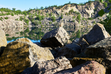 View on lake in flooded granite quarry with radon water. Mountain lake in the summer. Landscape with rock stones and reflection.