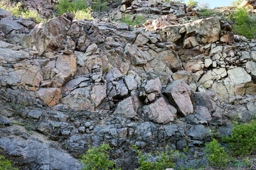 The stone mountains are covered with fresh bright green foliage of trees in early spring