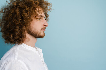 Young curly man with ginger hair posing and looking aside