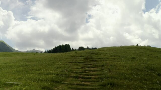 Aerial drone footage following a footpath in the Alps of Trentino Alto Adige, Italy on a cloudy day