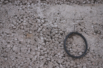 cement concrete wall with some garbage unnecesary rubber ring hanging on steel hook
