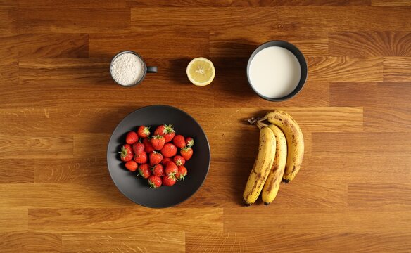 Zutaten für Sahneroulade mit Erdbeeren und Bananen auf Tisch von oben