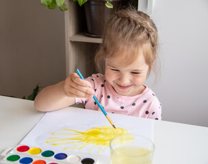 A happy girl paints the sun. The concept of children's creativity.
