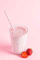 Fresh milkshake with strawberries on pink background. Summer drink with berries in a glass. Place for text.