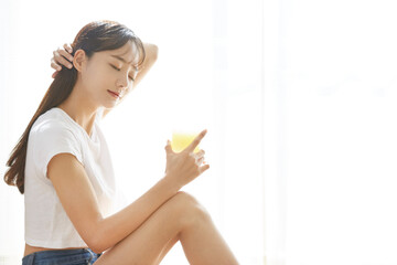 Naklejka premium 果物ジュースを飲む健康的な若い女性