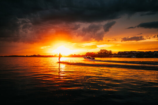 Man wake-boarding on a lake. Man water skiing at sunset.