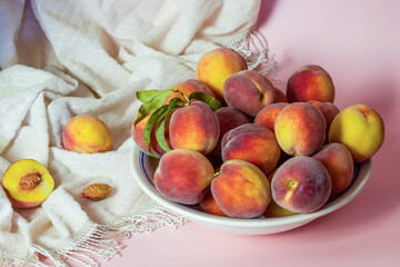 Plate with fresh peaches on pink background