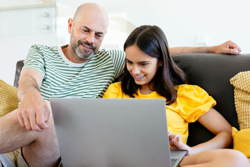 Happy father and teen daughter watching something in her laptop